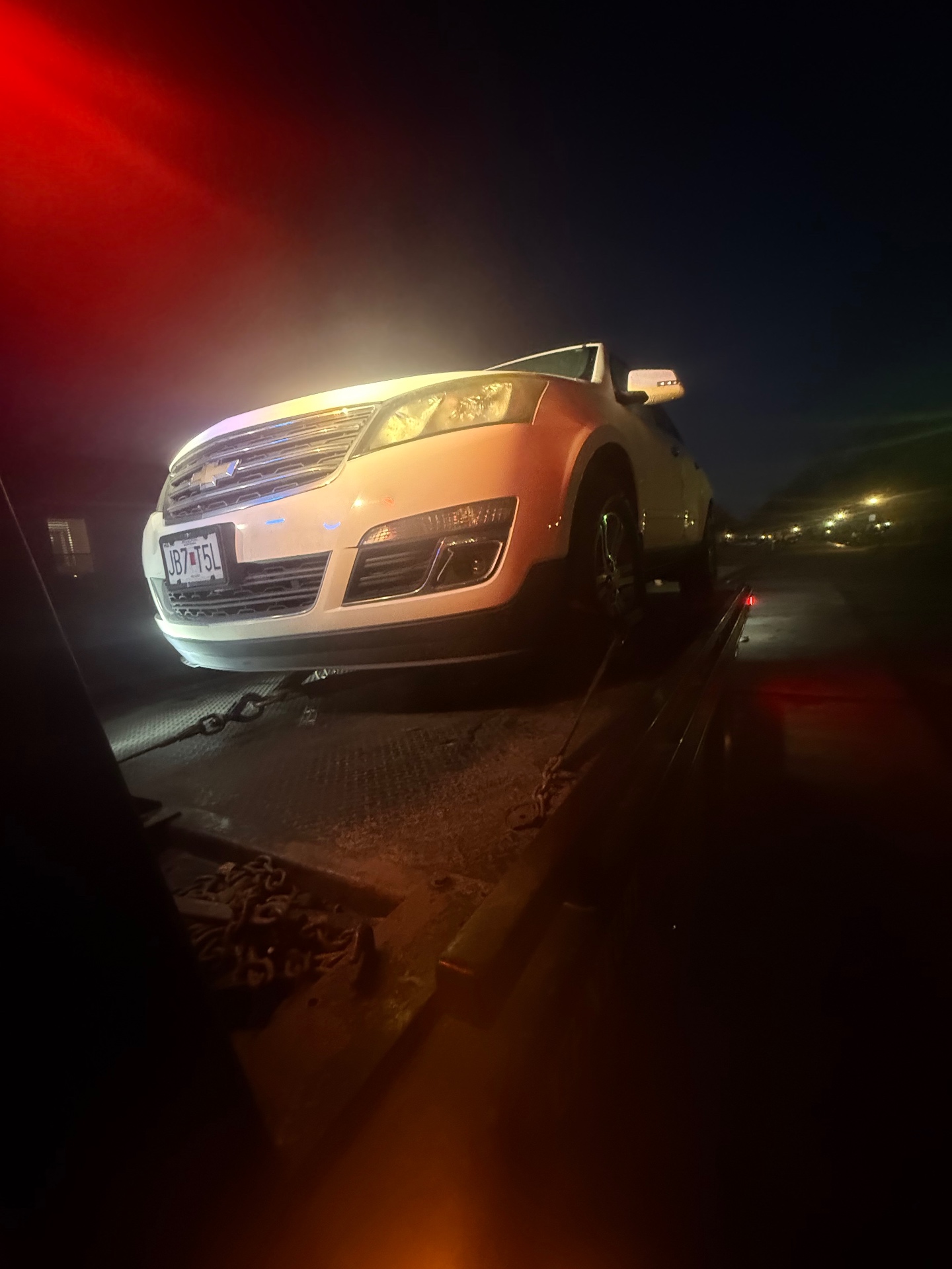 White SUV on a flatbed tow truck at night